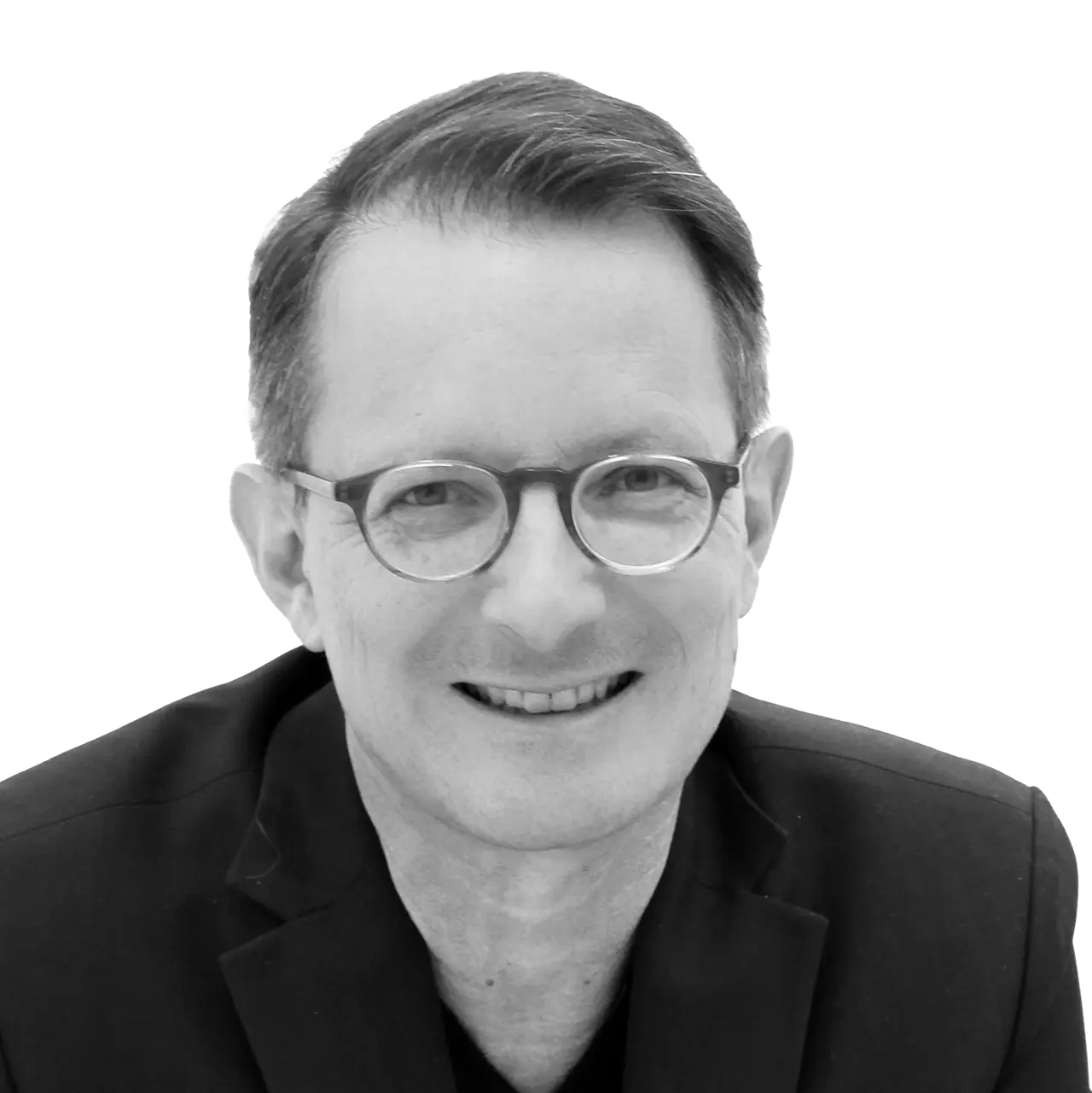 Porträt von Dr. Alexander King, lächelnd mit runder Brille und dunklem Sakko.